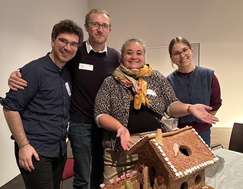 Mehrere Auszubildende stehen hinter ihrem selbst gebauten Lebkuchenhaus.