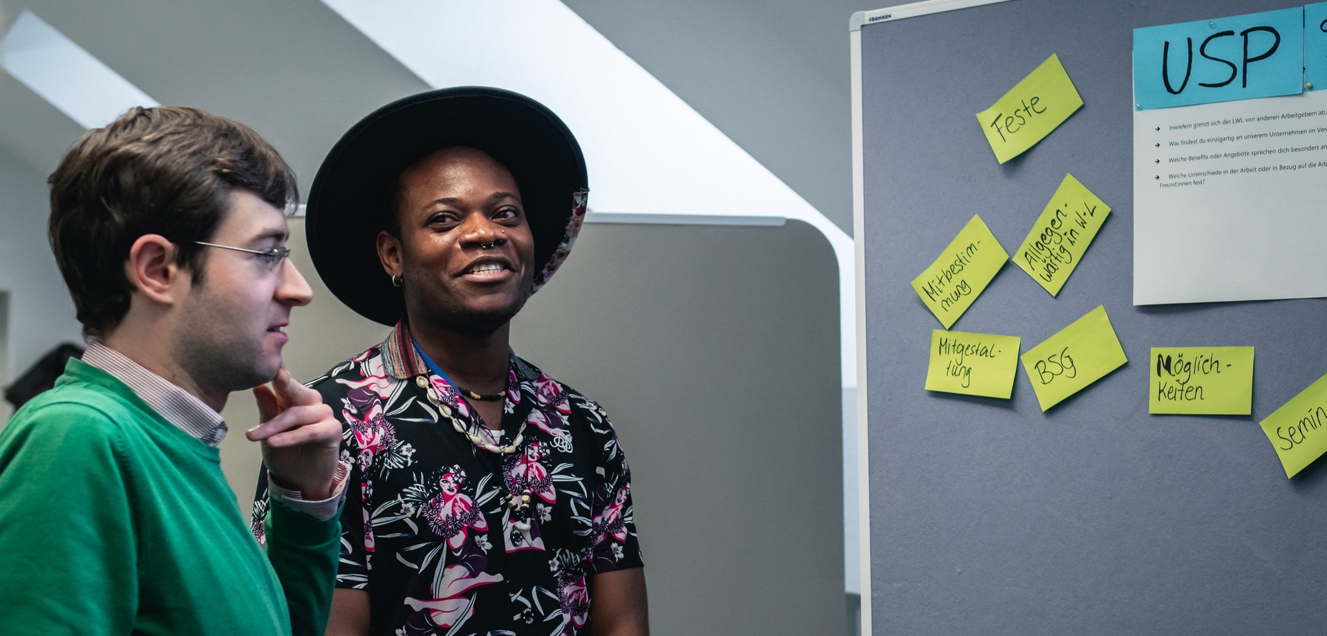 Zwei Auszubildende im Gespräch vor einer Wand mit vielen Post-it`s