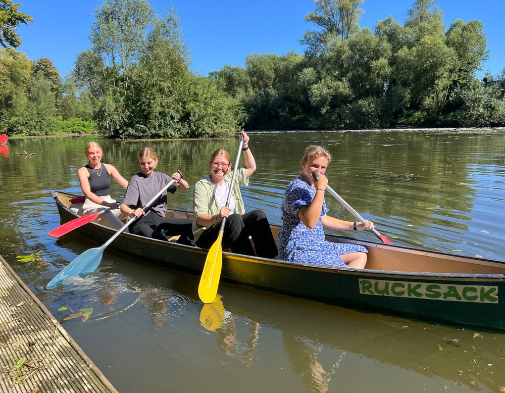 Vier junge Frauen fahren Kanu auf einem Fluss.